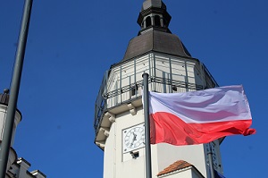 Powiewająca flaga Polski na tle wieży szydłowieckiego ratusza.