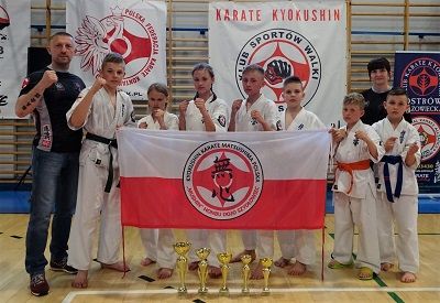 Zdjęcie grupowe zawodników i opiekunów UKS Karate Kyokushin "MUSHIN" Szydłowiec wraz ze zdobytymi pucharami.