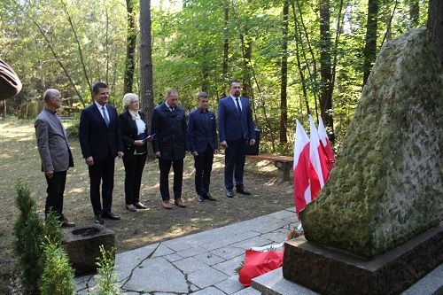 Delegacja składająca kwaity pod pomnikiem upaiemiątniającym tragedię w czasie II wojny Światowej.